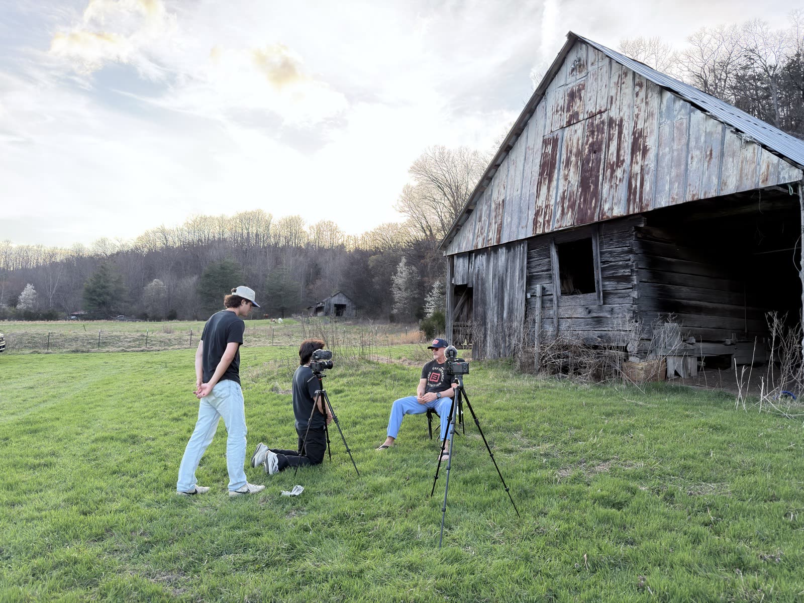 Golden-hour interview beside the barn — the subject in a camp chair, crew at two cameras.