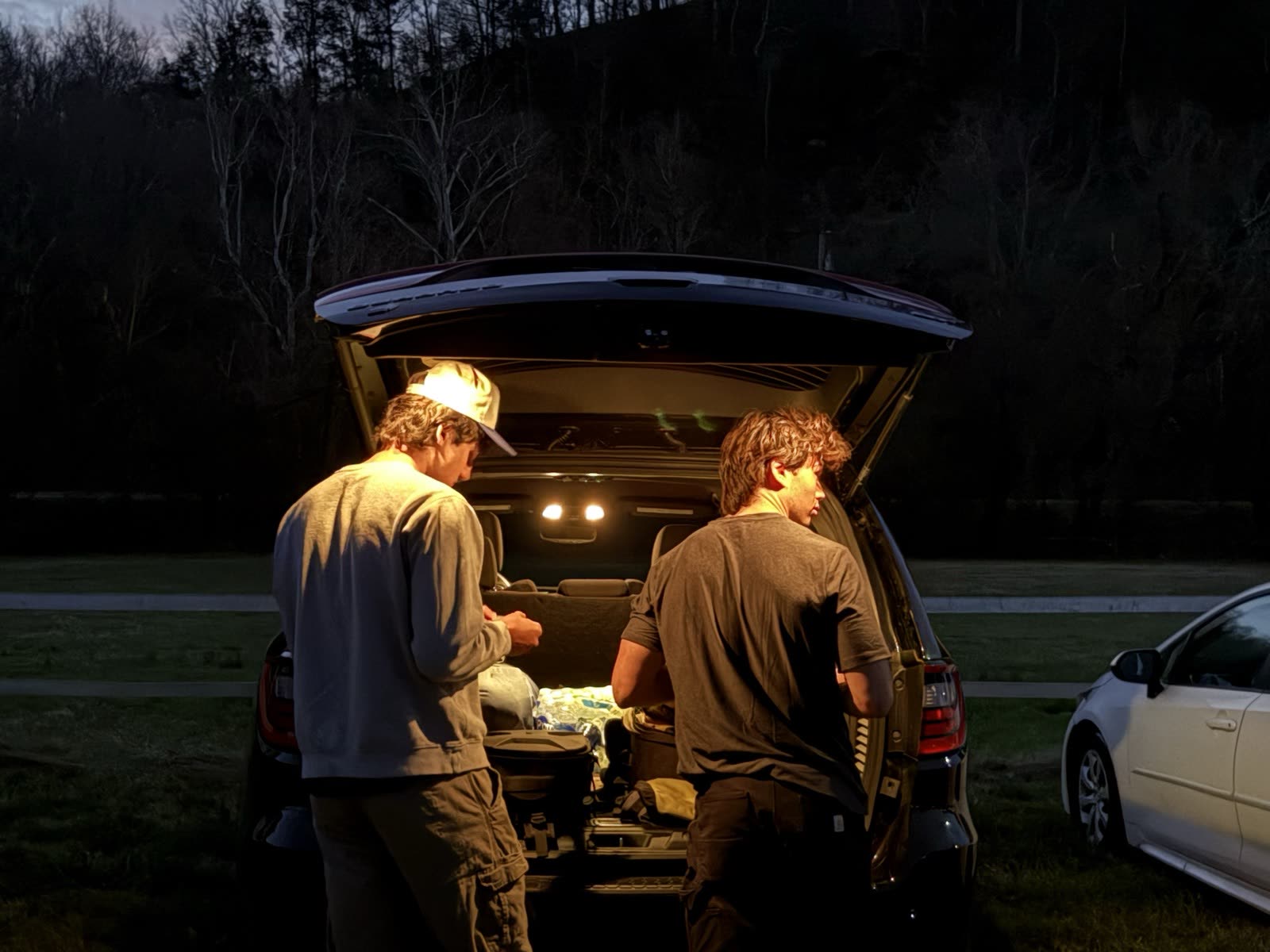 Loading gear from the trunk at dusk before a night shoot.
