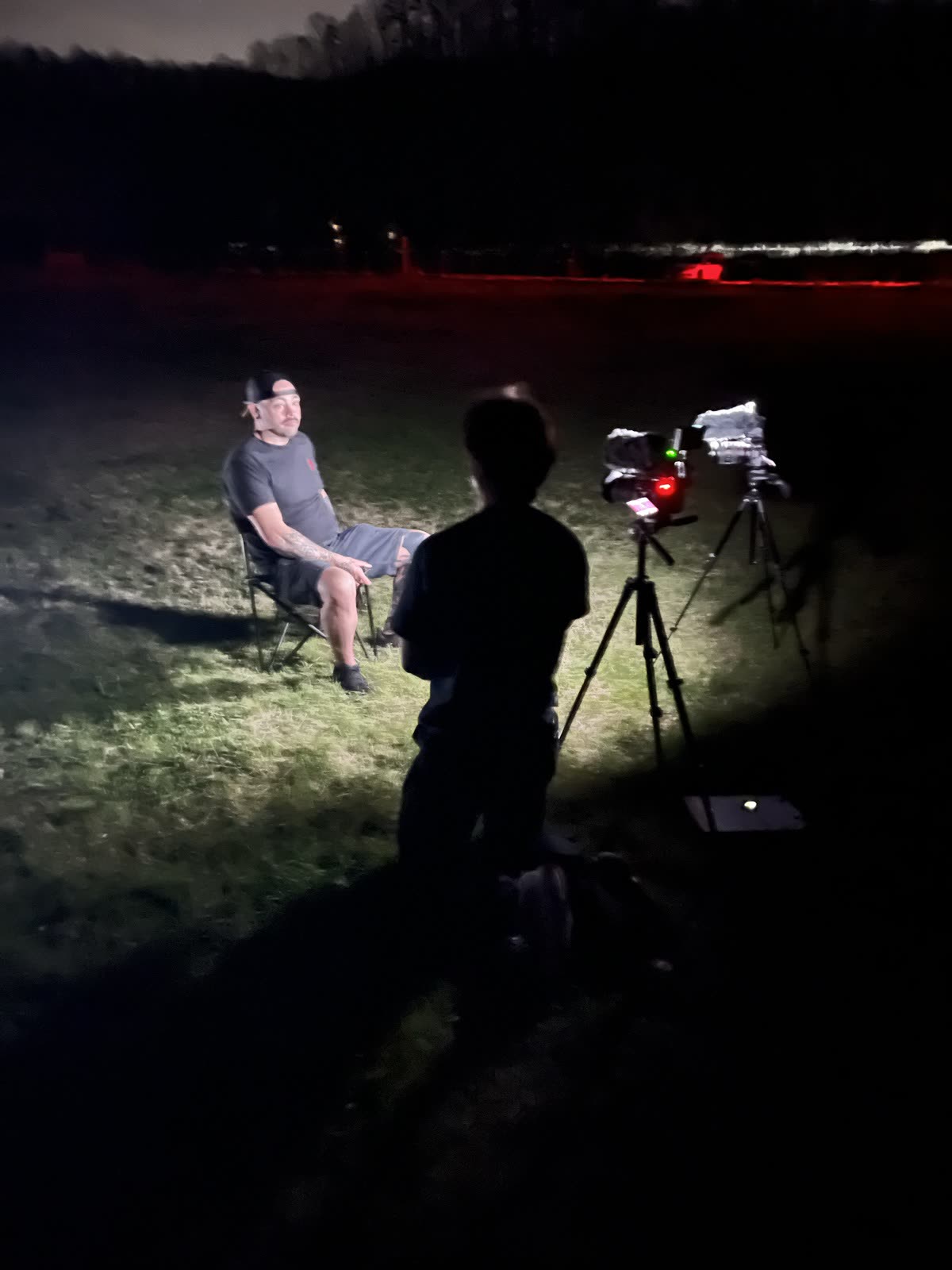 A night interview lit by a single work light at the edge of the course.