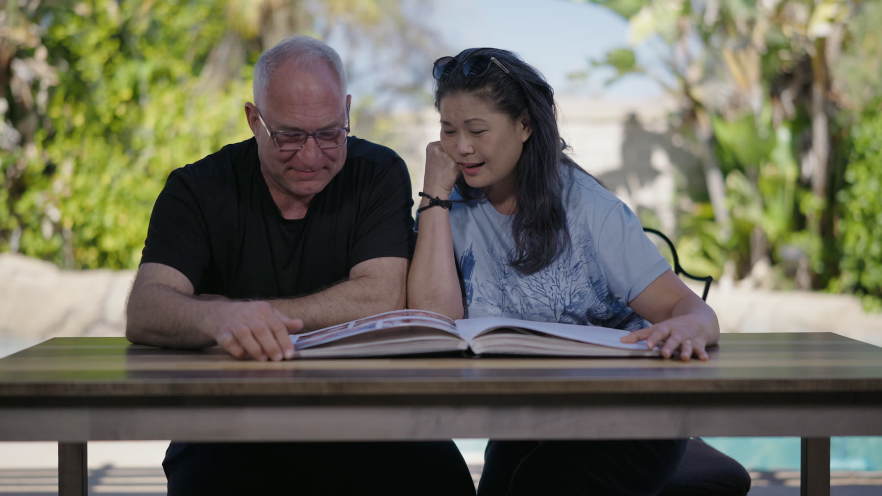 Dr. Vaughn Starnes and Ressia Lee sit at an outdoor table, looking through a photo book together.