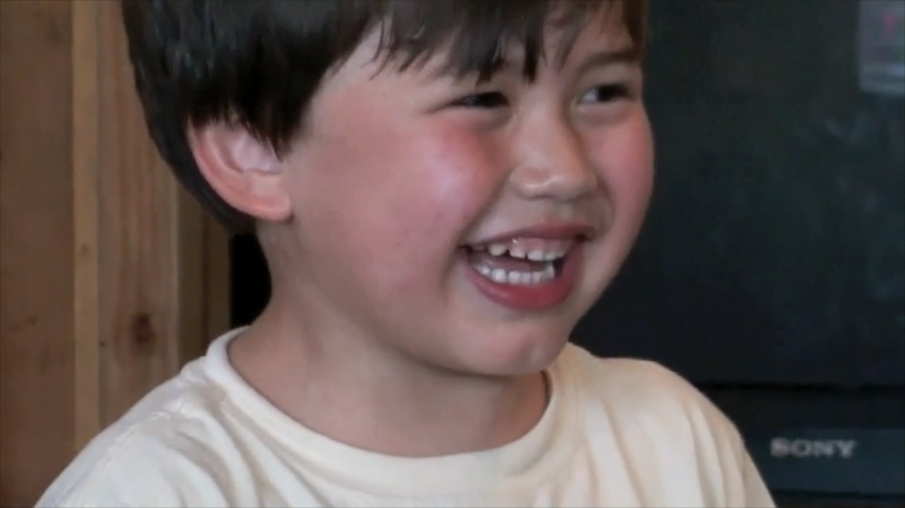 Christopher as a young boy, laughing, in an archival home-video frame.