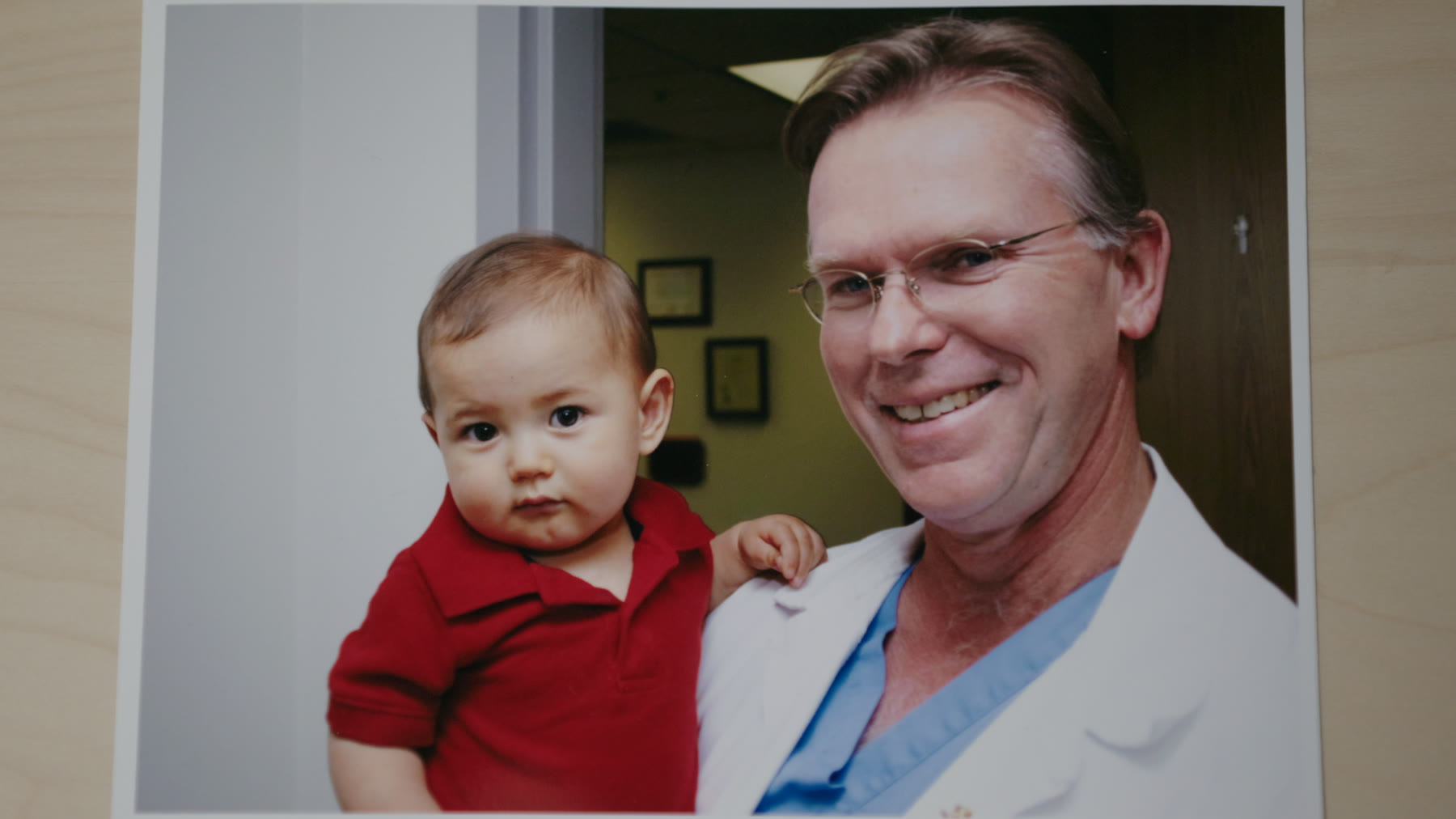 An archival photograph of Dr. Vaughn Starnes in his white coat holding the baby at the hospital.