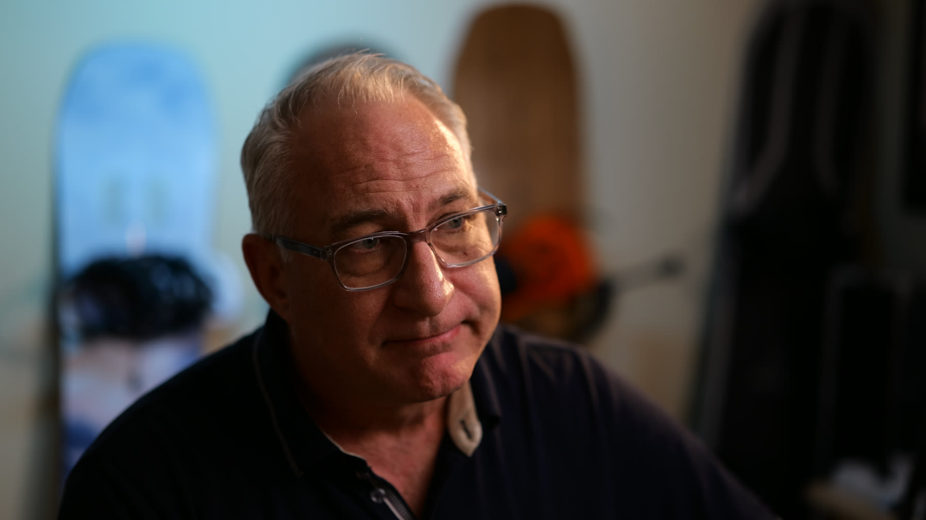 An older man in glasses in a soft-lit, contemplative interview portrait.